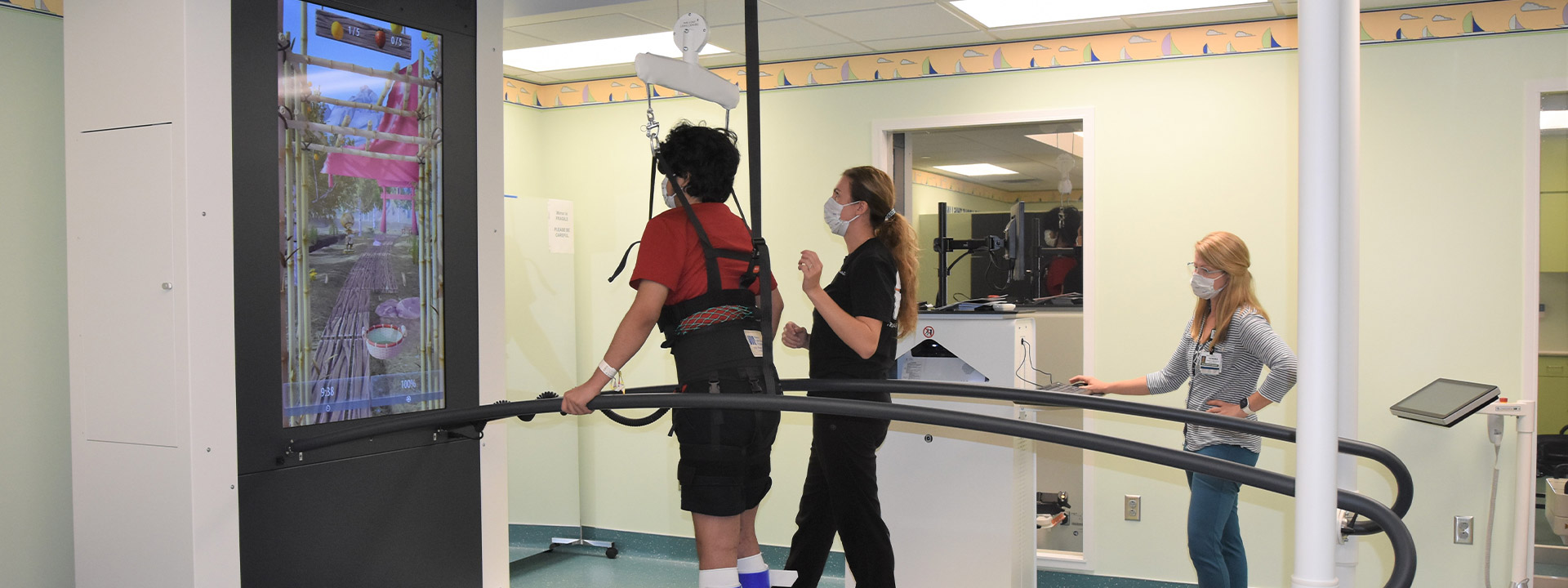 Teen patient on treadmill with large video screen on wall