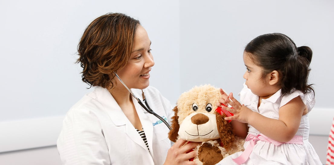Doctor Karen Evans with toddler holding big fluffy dog during checkup 