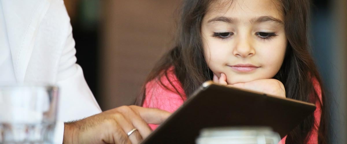 Girl with brown hair looking at something on a digital tablet