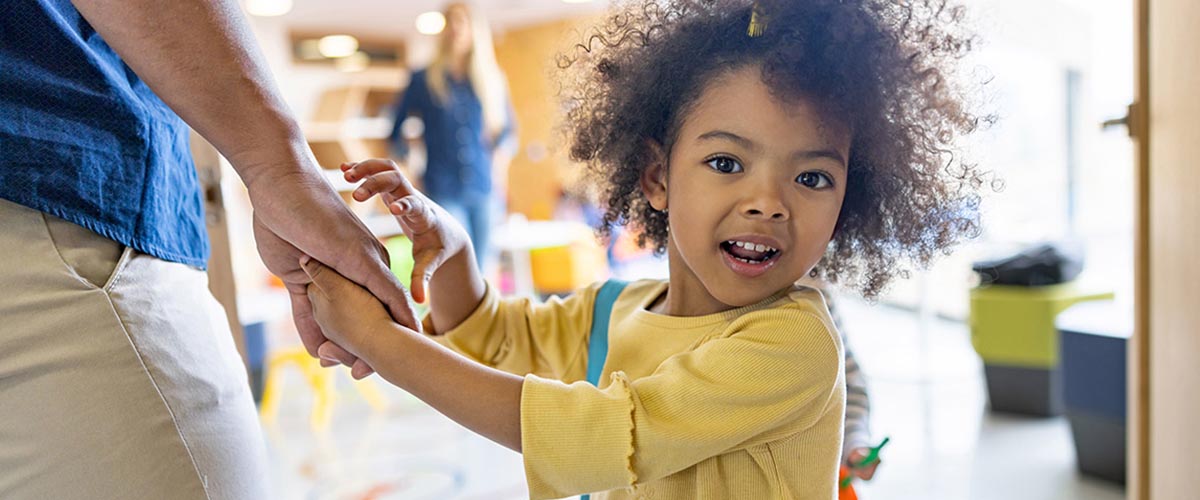Boy with afro holding mom’s hand and looking toward camera