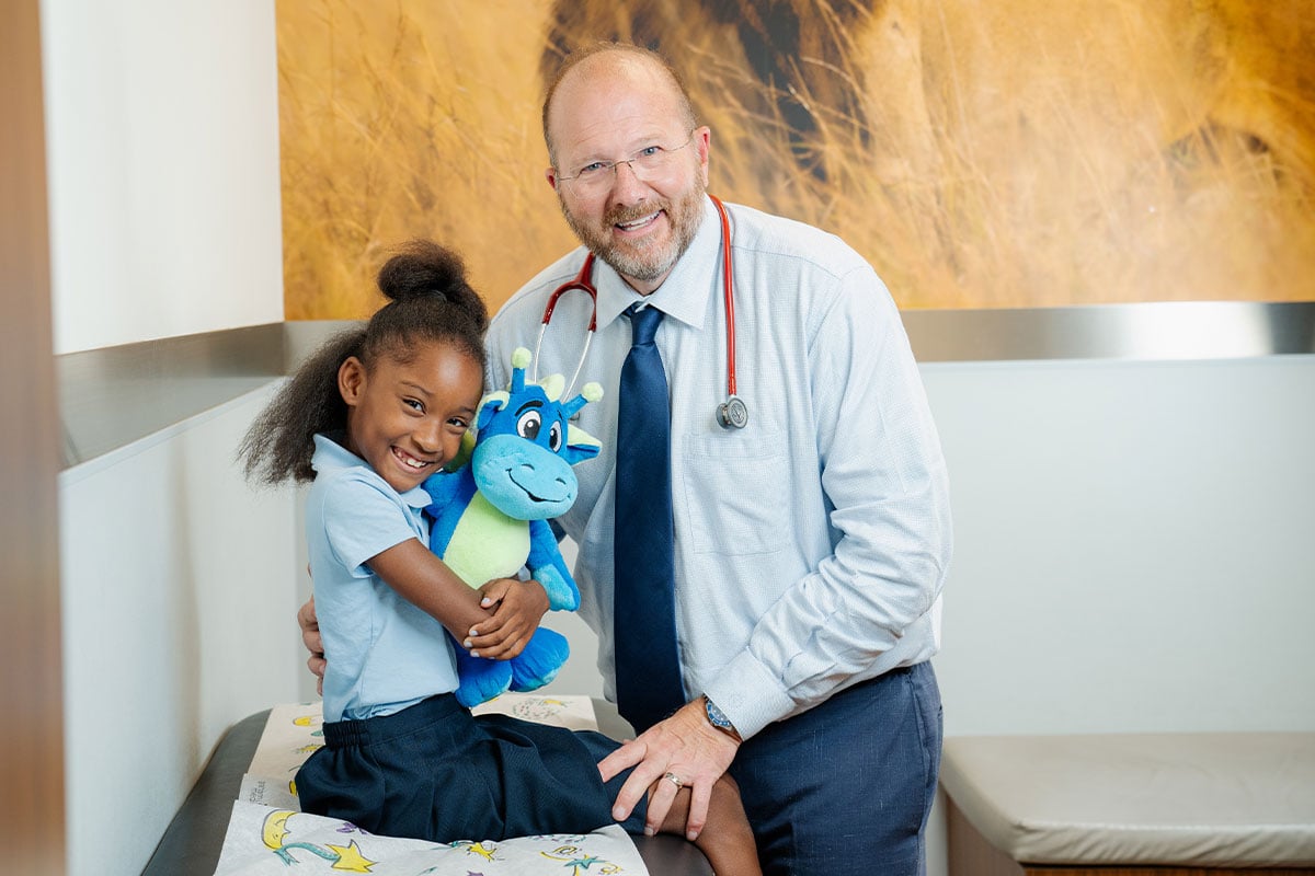 Pediatric physician smiling with a child at a primary care office in Plano, Texas