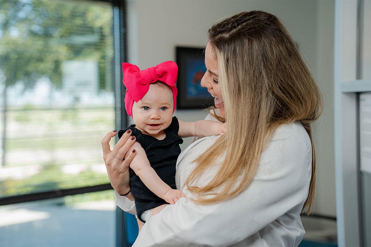Primary care physician holding a baby at a pediatric office in Fort Worth