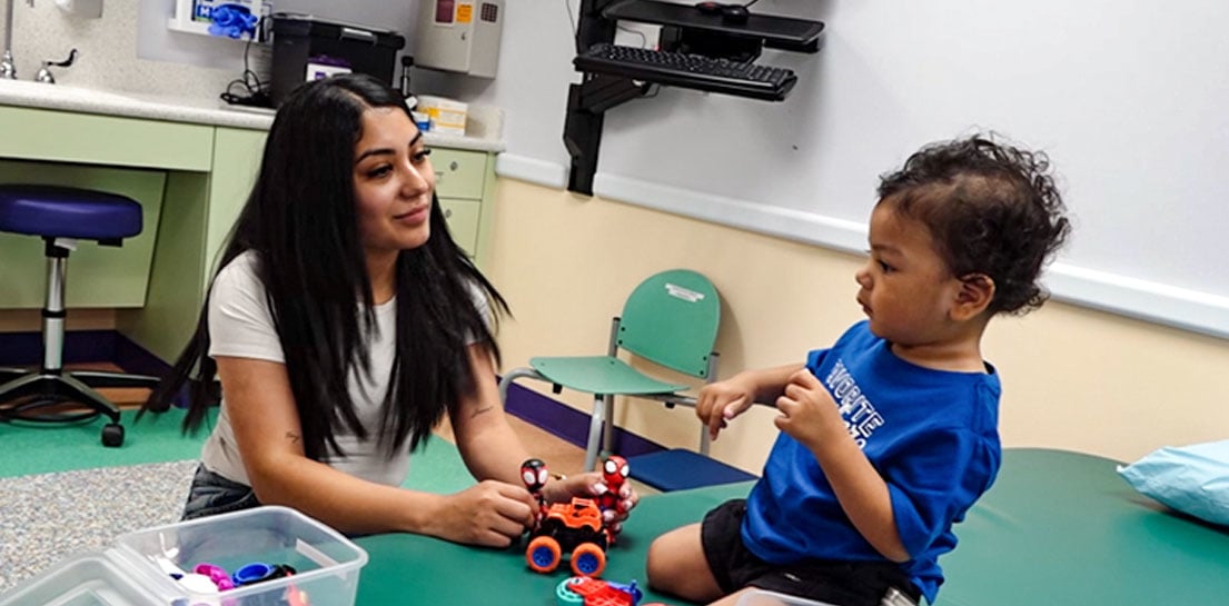 young boy wearing a blue shirt playing with spider man toys