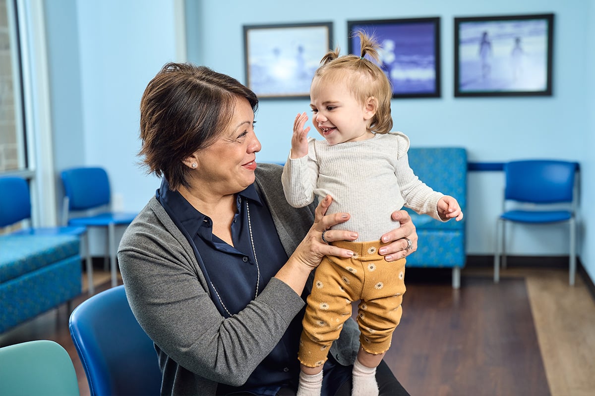 A primary care physician in Lewisville holding and laughing with a baby girl