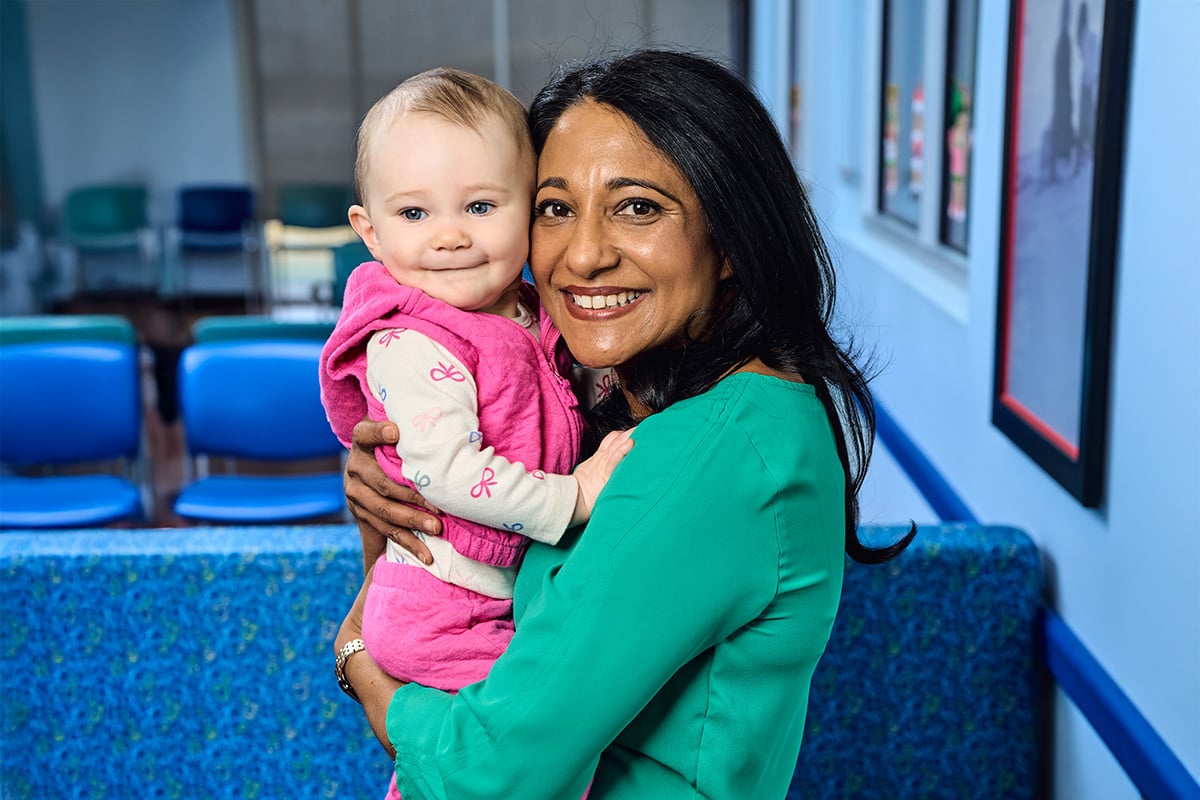 A pediatrician in the Castle Hills neighborhood holding a baby girl wearing pink
