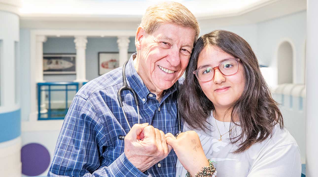 Smiling doctor with stethoscope and young female patient with glasses making a pinky promise