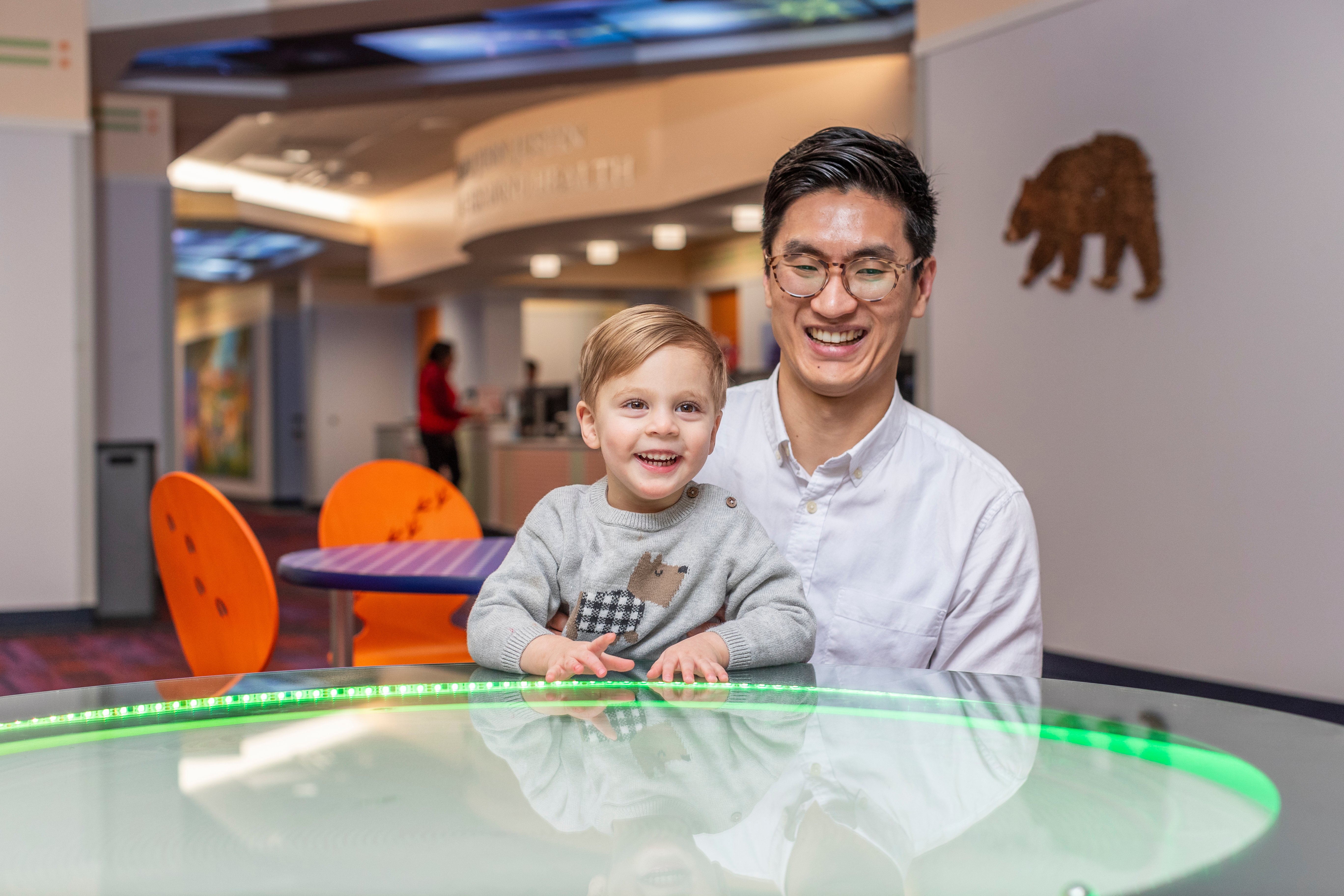 Young boy wearing a grey sweater with a dog on it sitting at a table with green lights